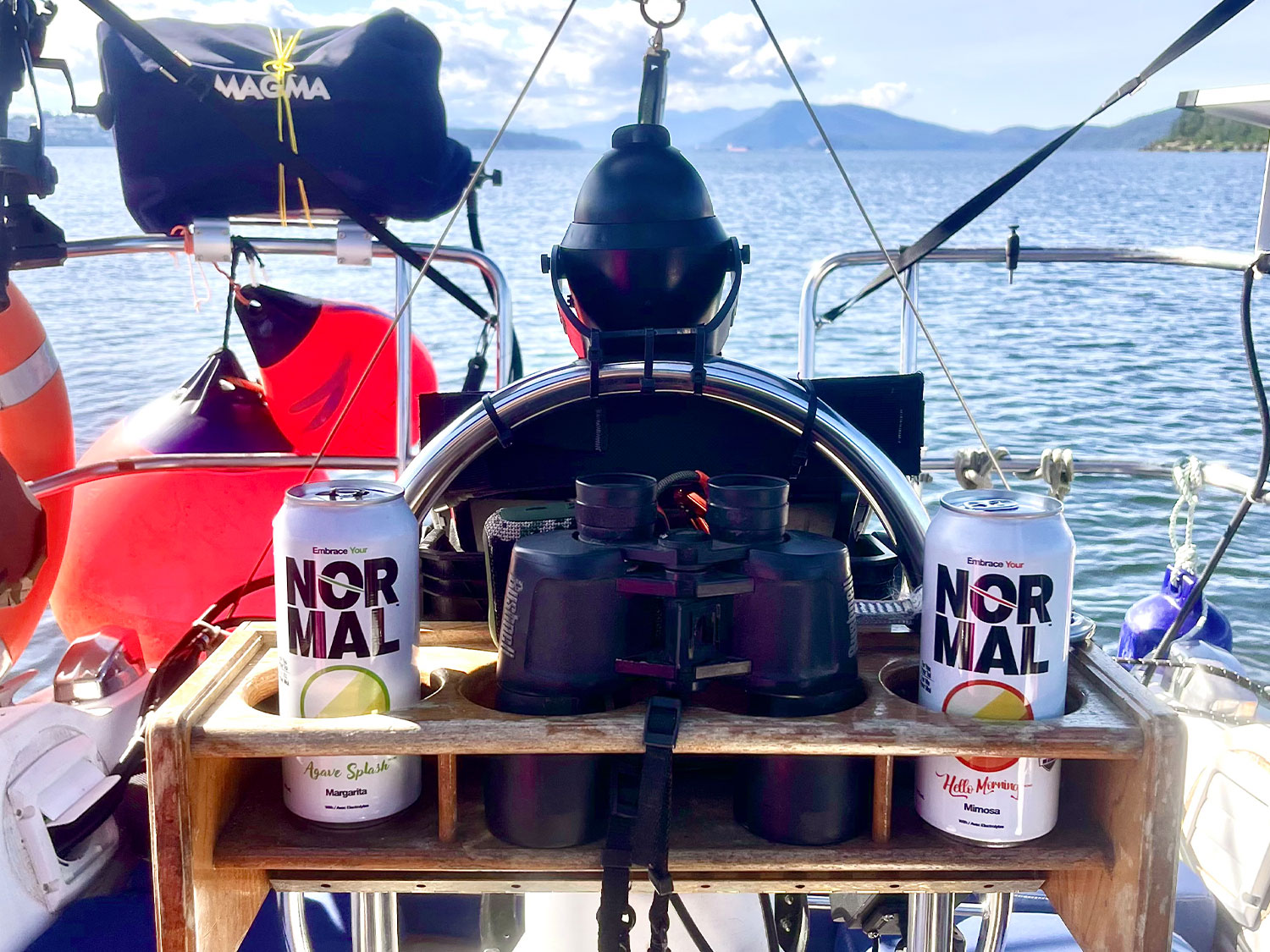 A boat navigates Vancouver island, BC with Normal Beverage Agave Splash Margarita and a Hello Morning Mimosa can in the cup holder